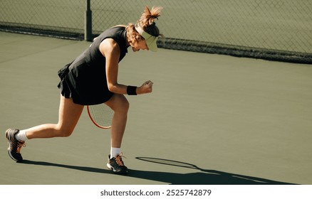 Blonde woman with an athletic build making a fist pump in celebration on an outdoor tennis court. - Powered by Shutterstock