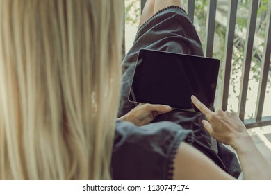 Blonde Woman From The Back Reading A Tablet Ipad Device In A Relaxing Holidays Way, Full Screen