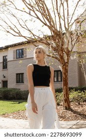 blonde woman in black tank top looking away while standing near house in Miami