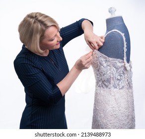 Blonde Woman In Blue Pin Striped Dress Mending A White Wedding Gown Dress