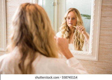 Blonde Woman Brushing Her Teeth In The Bathroom At Home