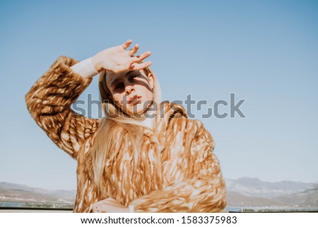 Blonde junge Frau mit Hut und Sonnenbrille, die bei Sonnenuntergang im Wald mit einem Mobiltelefon ein Foto macht.