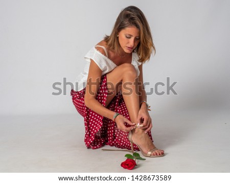 Blonde woman dressed in flamenco buckle her shoes on white background