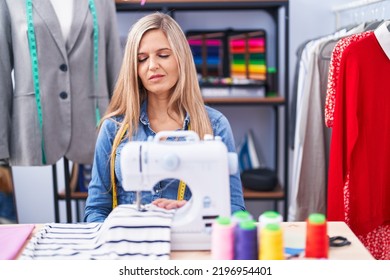 Blonde Woman Dressmaker Designer Using Sew Machine Looking Sleepy And Tired, Exhausted For Fatigue And Hangover, Lazy Eyes In The Morning. 