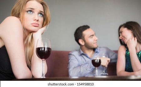 Blonde woman feeling jealous of couple flirting beside her in a bar - Powered by Shutterstock