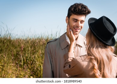 Blonde Woman In Hat Touching Face Of Man In Trench Coat