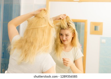 Blonde Woman Having Problems With Greasy Oily Hair Looking At Herself In Bathroom. Female Showing Scalp, Scratching Herself, Dandruff Problem.