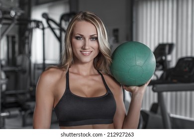 Blonde Woman Holding Medicine Ball In Gym