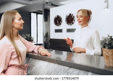 Blonde Woman Hotel Guest Checking-in At Front Desk In Hotel