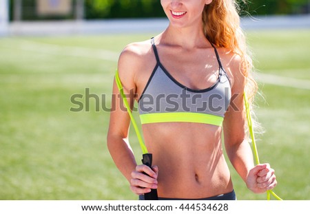 Blonde woman with jumping rope. Beautiful young sports woman standing with a jumping rope in her hands with a stadium as background