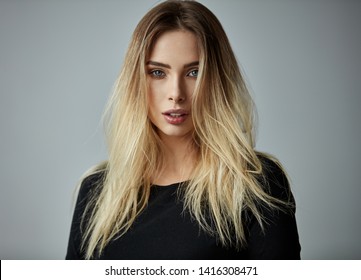 Blonde Woman With Long Straight Hair Looking At Camera Isoalted On Gray Background