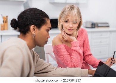 Blonde Woman Looking At African American Boyfriend Using Laptop