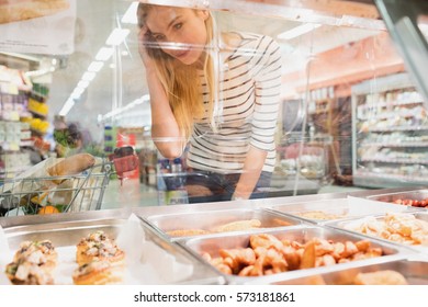 Blonde Woman Looking At Prepared Meal Buffet At Grocery Store