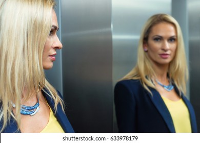 Blonde woman looks in the mirror in the elevator - Powered by Shutterstock