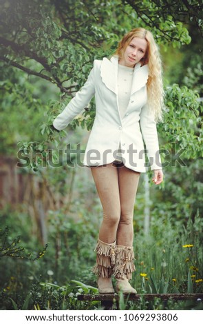 blonde woman on a green background in white clothes, cool summer, shy and inquisitive.