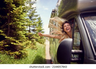 Blonde Woman On The Window Of An Rv With Hands Out Smiling Enjoying Ride.Transport, Roadtrip, Nature Concept.