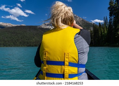 Blonde woman paddles on the front of a canoe on Emerald Lake in Yoho National Park, British Columbia Canada