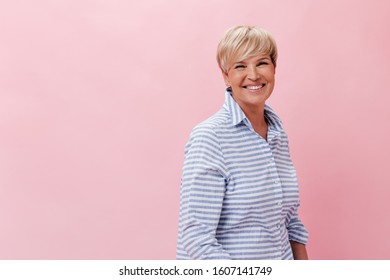 Blonde woman in plaid shirt laughing on pink background