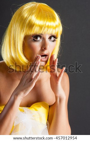 Blonde woman posing like plastic Barbie doll, on gray background
