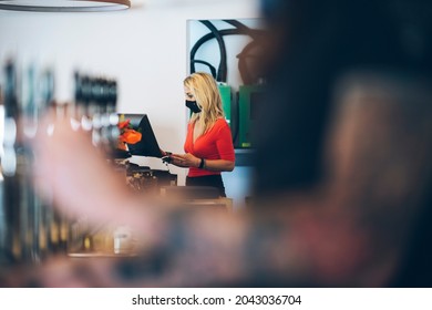 Blonde Woman With Red Shirt And Protective Mask At The Bar Cashier.  Payments To The Pub. Covid-19, Virus, Restaurant