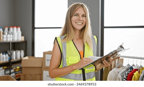 Blonde woman in safety vest holding clipboard in warehouse - Powered by Shutterstock