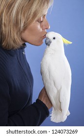 blonde woman showing affection to his white cockatoo