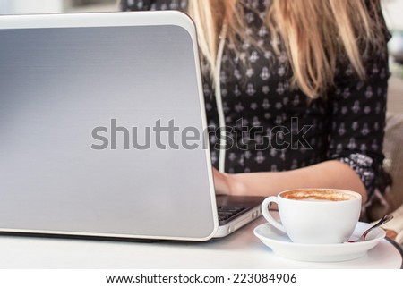 Blonde woman sitting in a cafe with cup of coffee and notebook
