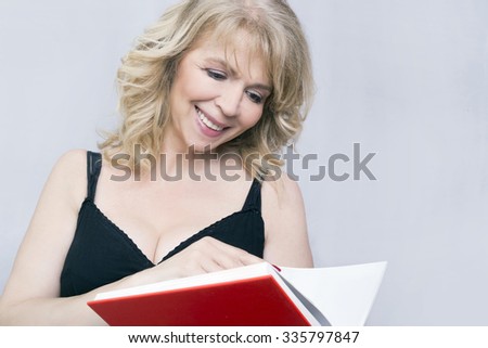 Blonde woman smiling and reading a book