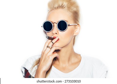 Blonde woman in sunglasses and white t-shirt smoking cigar.  White background, not isolated