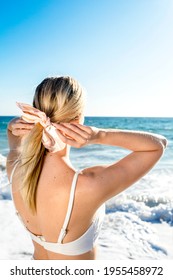 Blonde Woman Tying A Ponytail At The Beach Back View