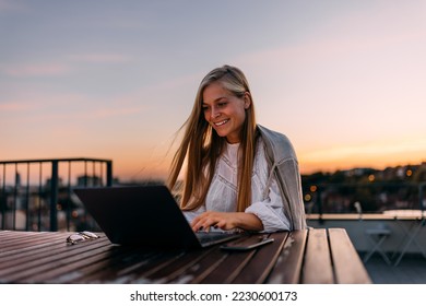 Blonde woman working over the laptop, being on the terrace, outdoor. - Shutterstock ID 2230600173