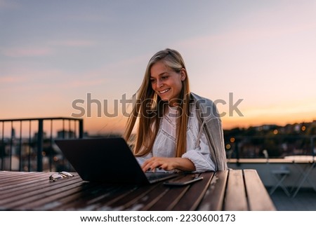 Blonde woman working over the laptop, being on the terrace, outdoor.