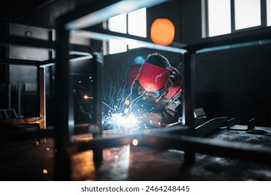 Blonde woman works as a welder in workshop, operating welding machine, wearing protective clothing and a welding mask. - Powered by Shutterstock