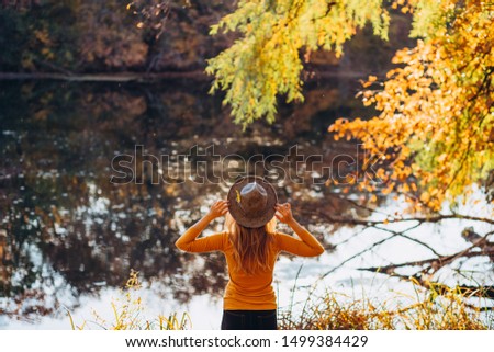 blonde in a yellow jacket on a background of autumn nature. the frame is lit by sunlight. A young woman in a gray hat looks at the autumn forest. Portrait of a woman in autumn