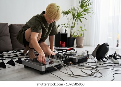 Blonde Young Short Haired Woman Turns The Regulators At The Dj Console Or Controller. Top View Of Female Producer At Home Studio With Modern Electronic Instruments