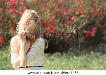 Blonde Young Woman in Spring Garden. Girl with Flying Hair lovely Smiling and Enjoying Blossoming Nature