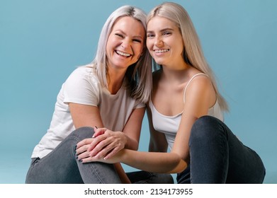 Blondehaired Mom and teenager daughter smiling on colorful backgroung. studio shoot with copy space