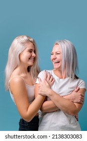 Blondehaired Mom and teenager daughter smiling on colorful backgroung. studio shoot with copy space