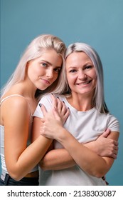 Blondehaired Mom and teenager daughter smiling on colorful backgroung. Middle studio shoot with copy space