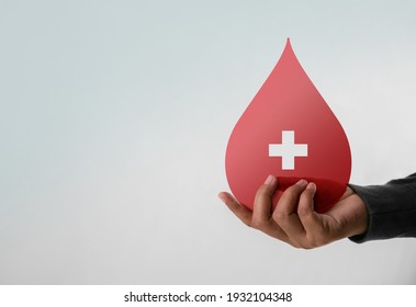 Blood Donation Concept. Help, Care, Love, Support. Hand Holding A Red Drop And Cross Sign