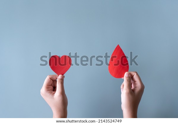 Blood donation or\
medical surgery concept. Human holding small piece of paper blood\
sign and a red heart\
shape.