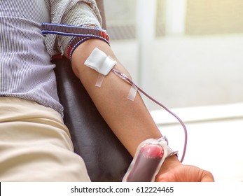 Blood donor at donation, transfusion. Close up right arm of a business man receiving blood in hospital. Healthcare and charity. Also concept image background for World blood donor day - June 14 .