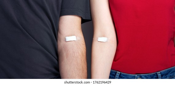 Blood Donorship. Man In Grey And Woman In Red T-shirt With Hands Taped Patch After Giving Blood