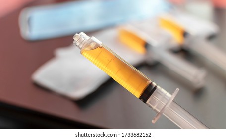 Blood plasma in a syringe on a blurred background. Blood plasma as a solution for the treatment of coronavirus. Platelet-rich plasma preparation for plasmolifting therapy. Selective focus.