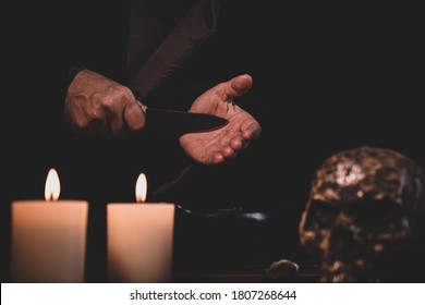 Blood Ritual, Preparation With An Knife, Occultly Witchcraft Or Cult, Dark Background With Candles And A Human Skull
