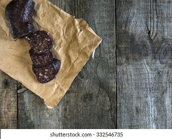 Blood sausage on crumpled wrapping paper on an old wooden table