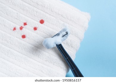 Blood Stains And Plastic Razor For Shaving On A White Towel. Daily Life Dirty Stain For Wash And Clean Concept. Isolated On Blue Background. High Quality Photo