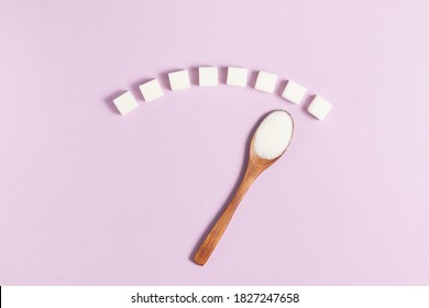 Blood sugar scale made from white sugar cubes and wooden eco spoon on pink background