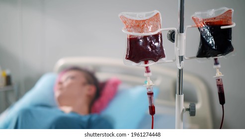 Blood transfusion to young woman patient in hospital bed. Female patient or donor lying in bed and receiving blood transfusion or donating blood in clinic ward