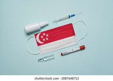 Blood Tube For Test Detection Of Virus Covid-19 Omicron Variant With Positive Result, Medicine Mask With Singapore Flag Superimposed And Vaccine.  New Variant Of The Covid-19 Omicron